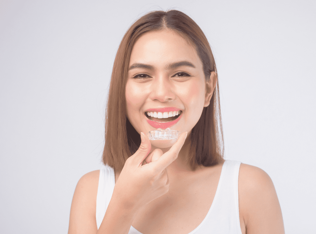 smiling women holding invisible braces clear aligners